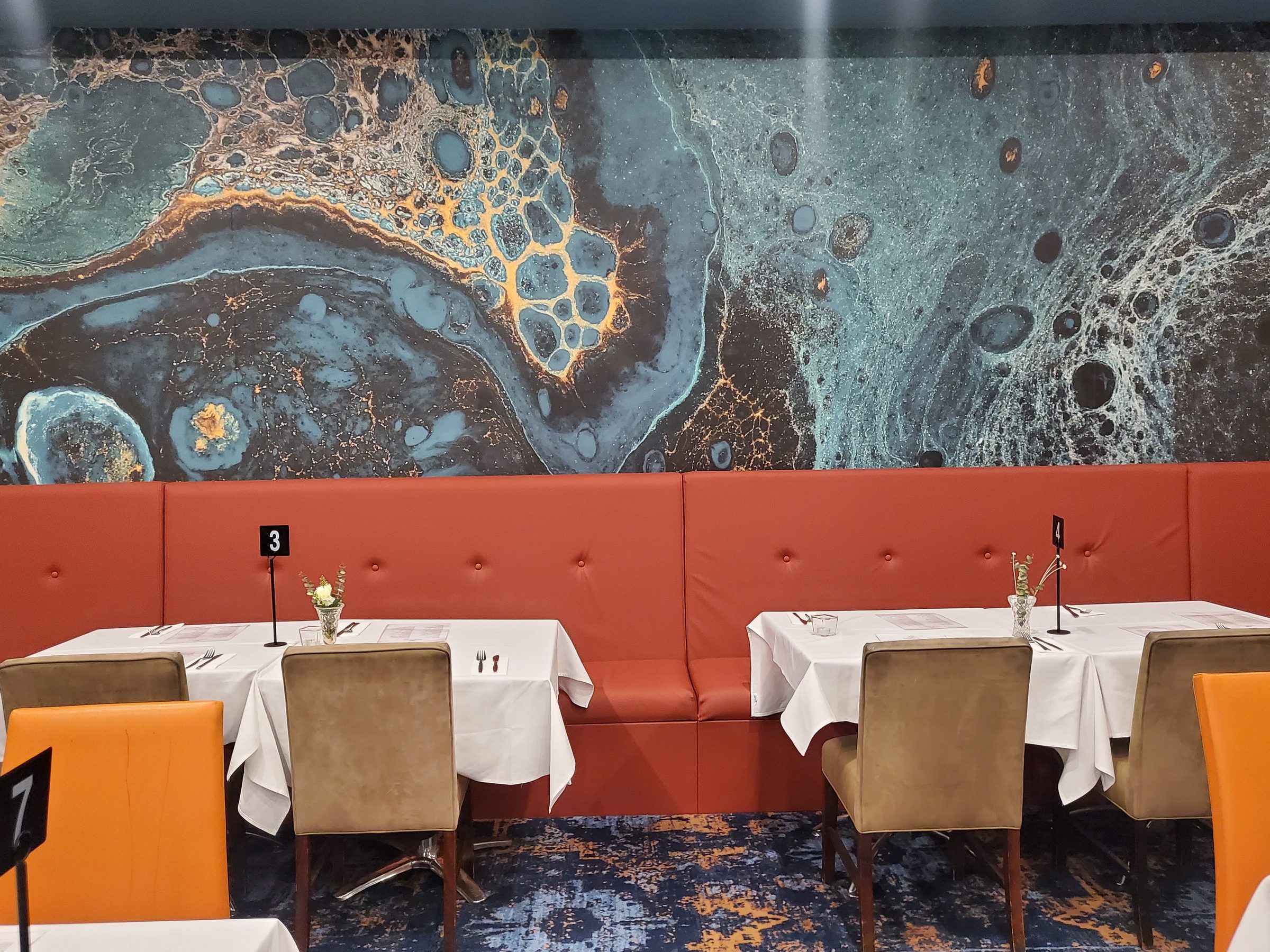 Tables set under the painted mural wall in the Holyrood Bistro